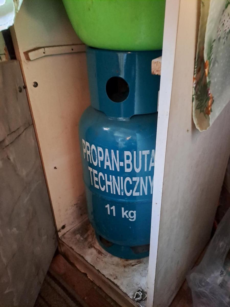 Otwarta zniszczona szafka, w której mieście się butla gazowa