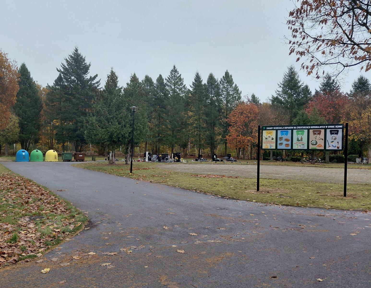 Stojak z grafikami jak segregować odpady, w oddali pojermniki kolorowe igloo, drzewa w jesiennych kolorach 