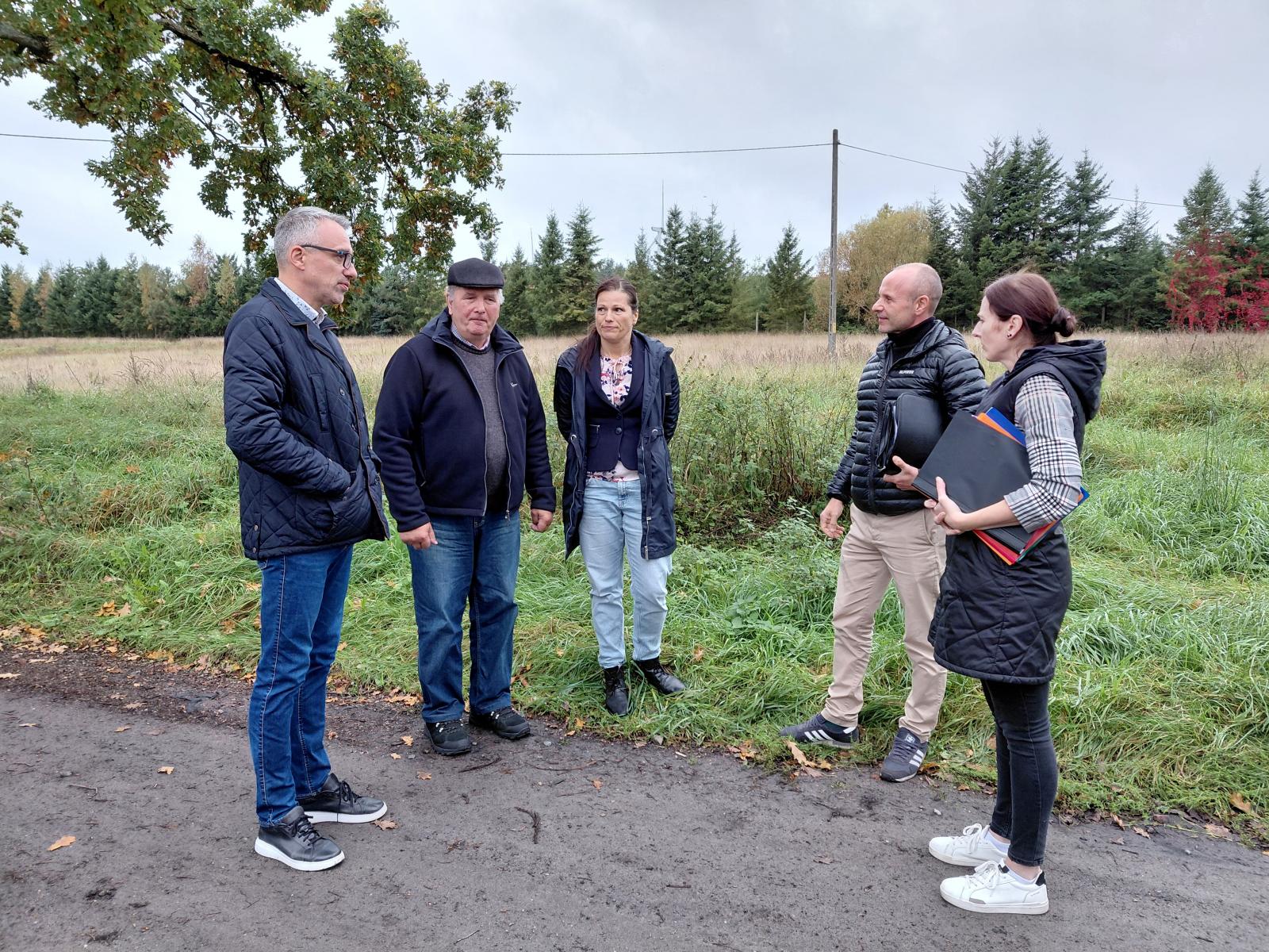 Pięć osób stoi na zewnątrz,na drodze polnej. od lewej: burmistrz Dębna, mężczyzna, kobieta, mężczyzna, kobieta