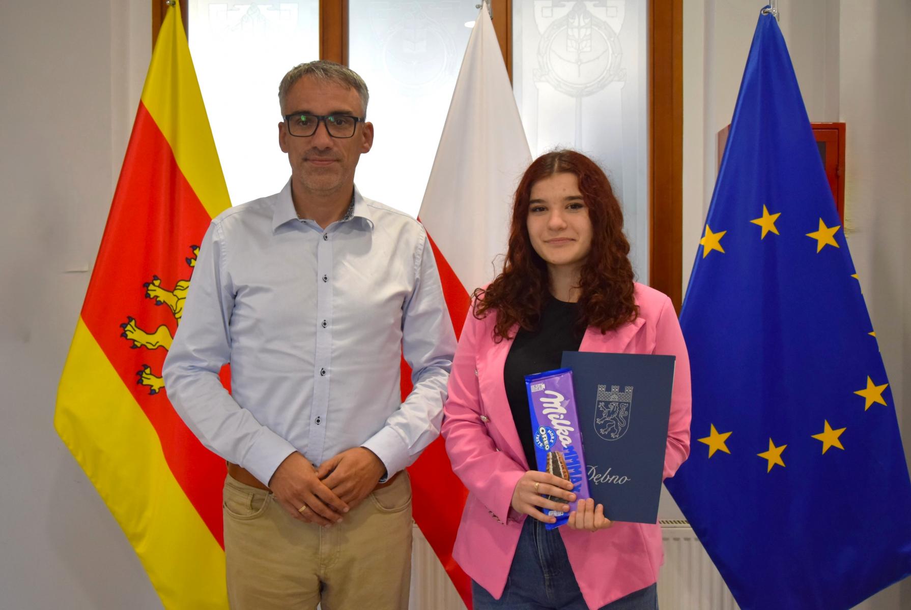 Aleksandra Sala od prawej stoi z burmistrzem. W tle flagi Dębna, Polski, UE