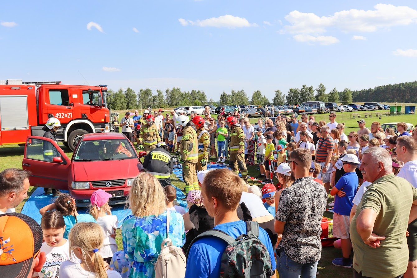 Pokaz ratwonictwa. samochód wokół niego strażacy, wokół nich gapie