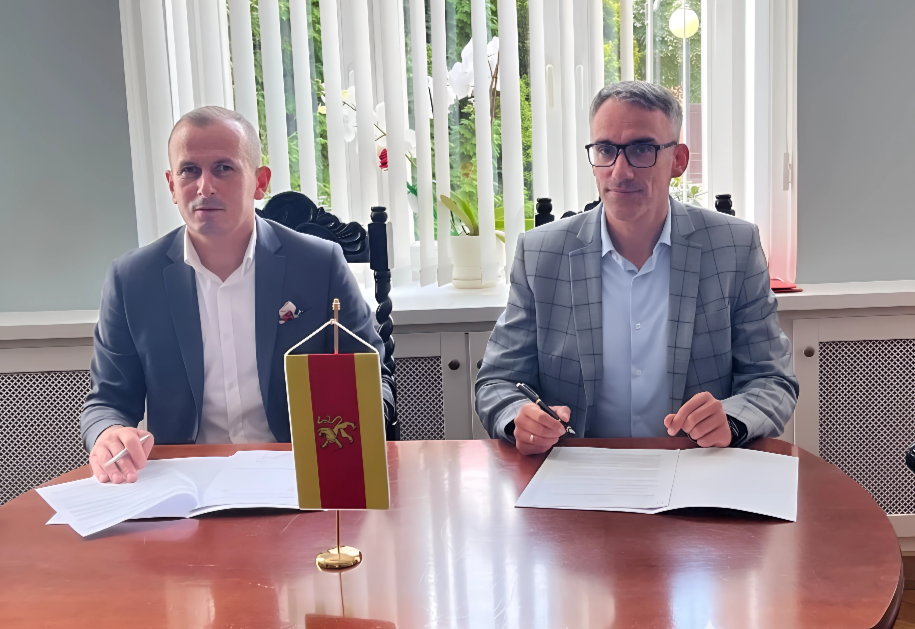 Dwóch mężczyzn siedzi przy stole. proporczyk gminy na stole