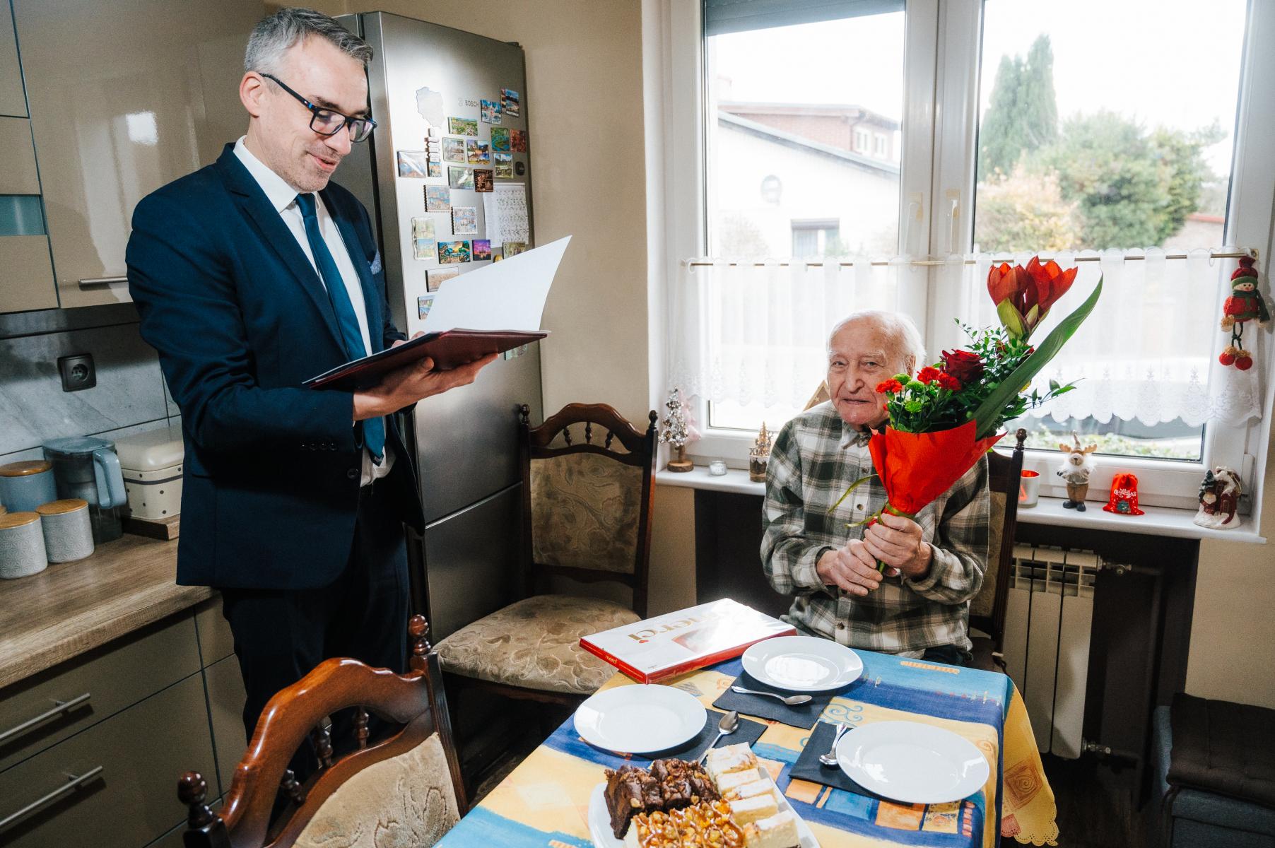 Burmistrz Dębna odczytuje list, Henryk Bondini siedzi trzymając kwiaty