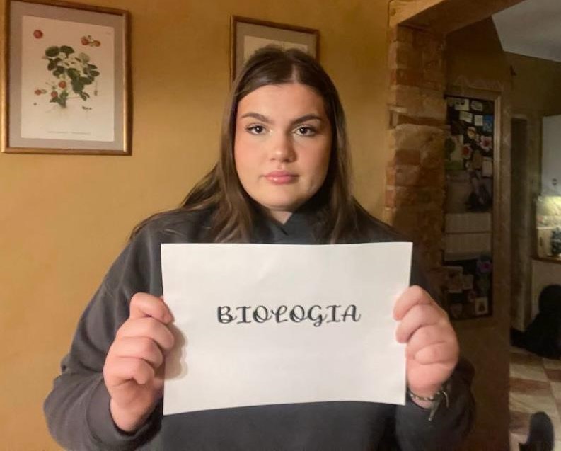 Uczennica trzyma kartkę z napisem biologia