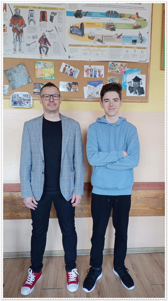 W klasie stoi nauczyciel i uczeń