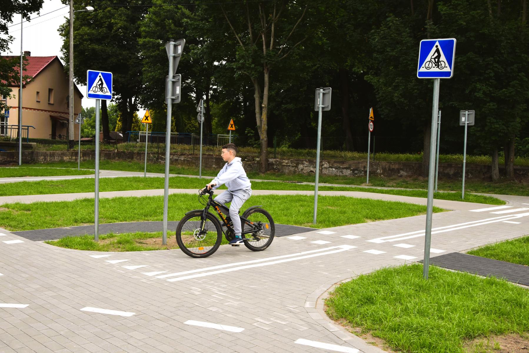 Chłopiec na rowerze jedzie po miasteczku rowerowym  