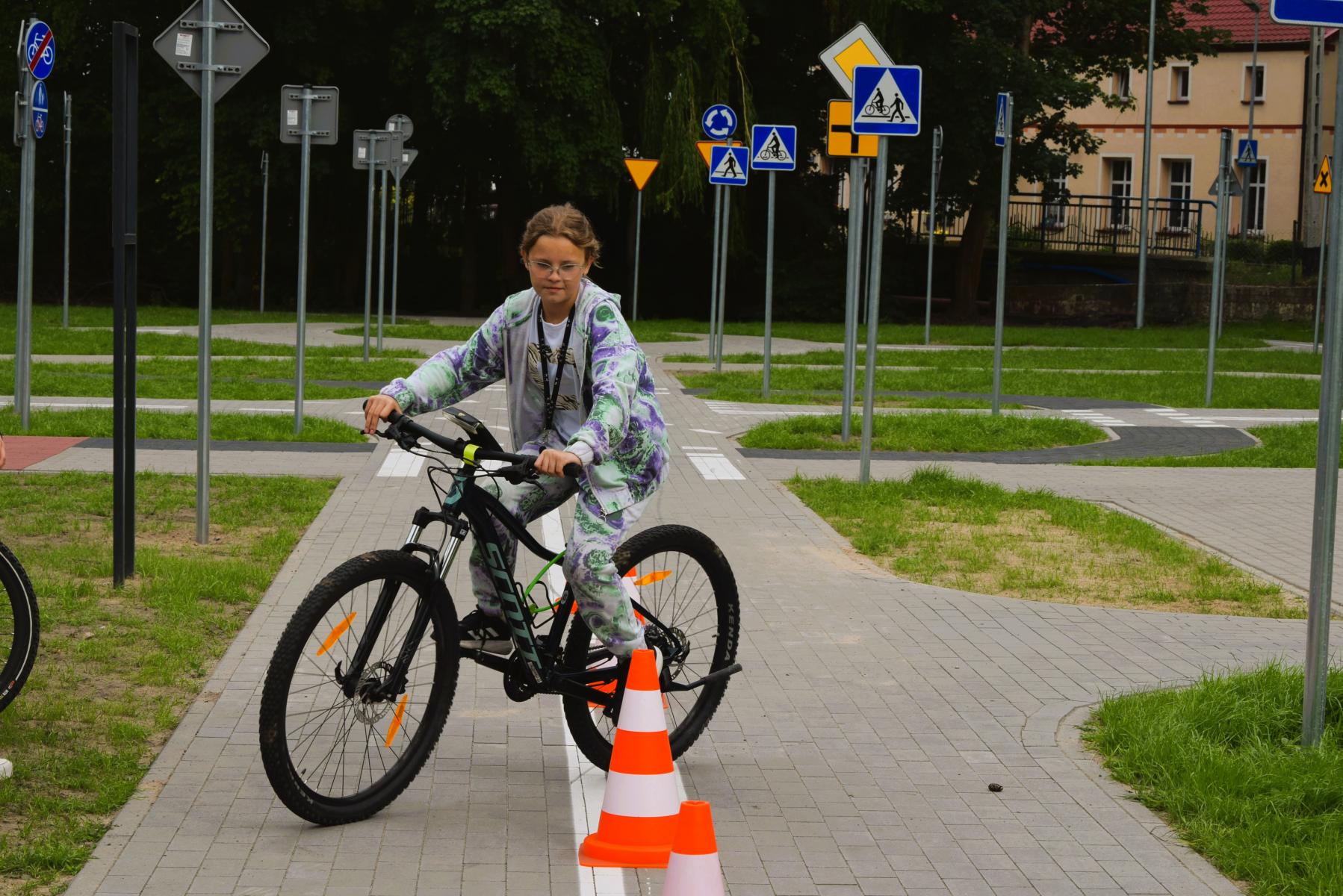 Uczennica jedzie rowerem między pachołakami