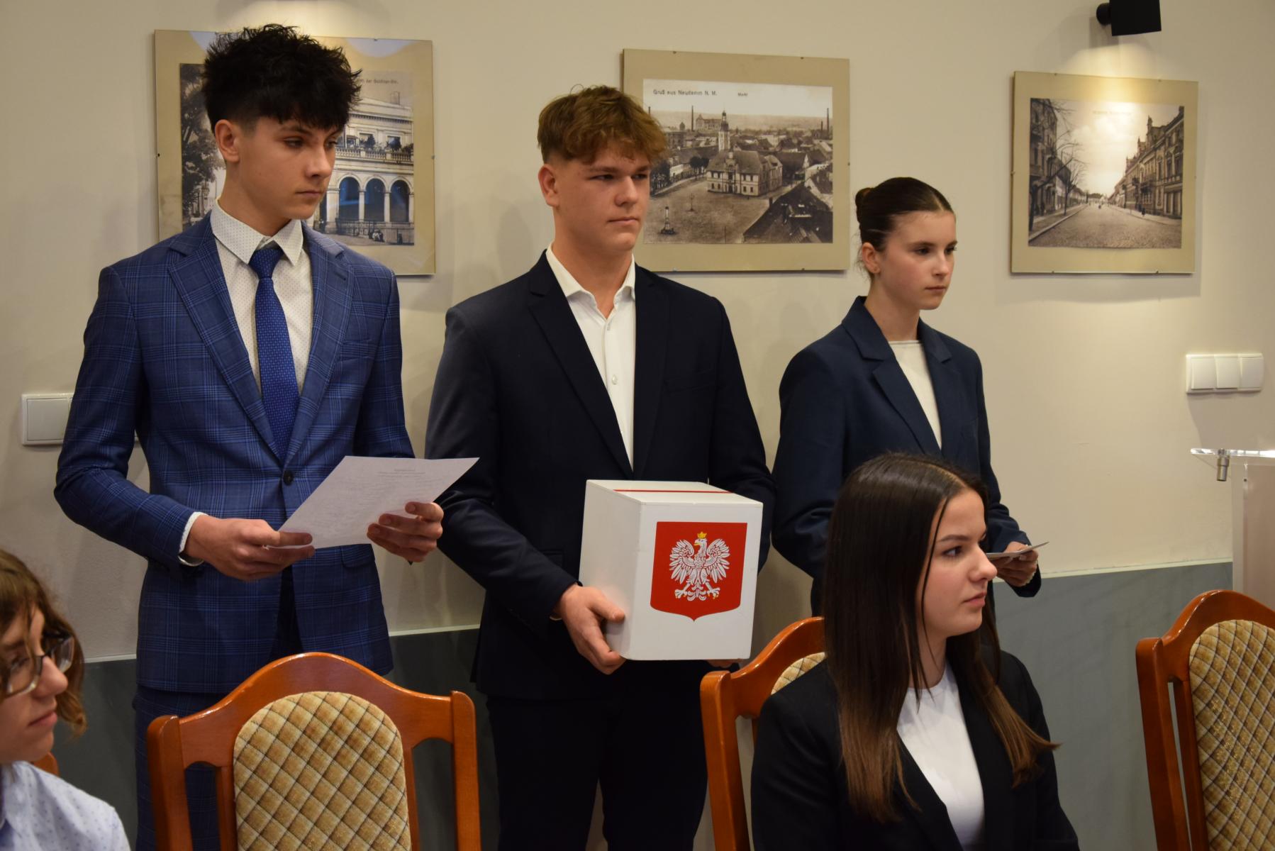 Od lewej: dwóch młodych chłopaków, dziewczyna, chłopak w srodku trzyma mała urnę 