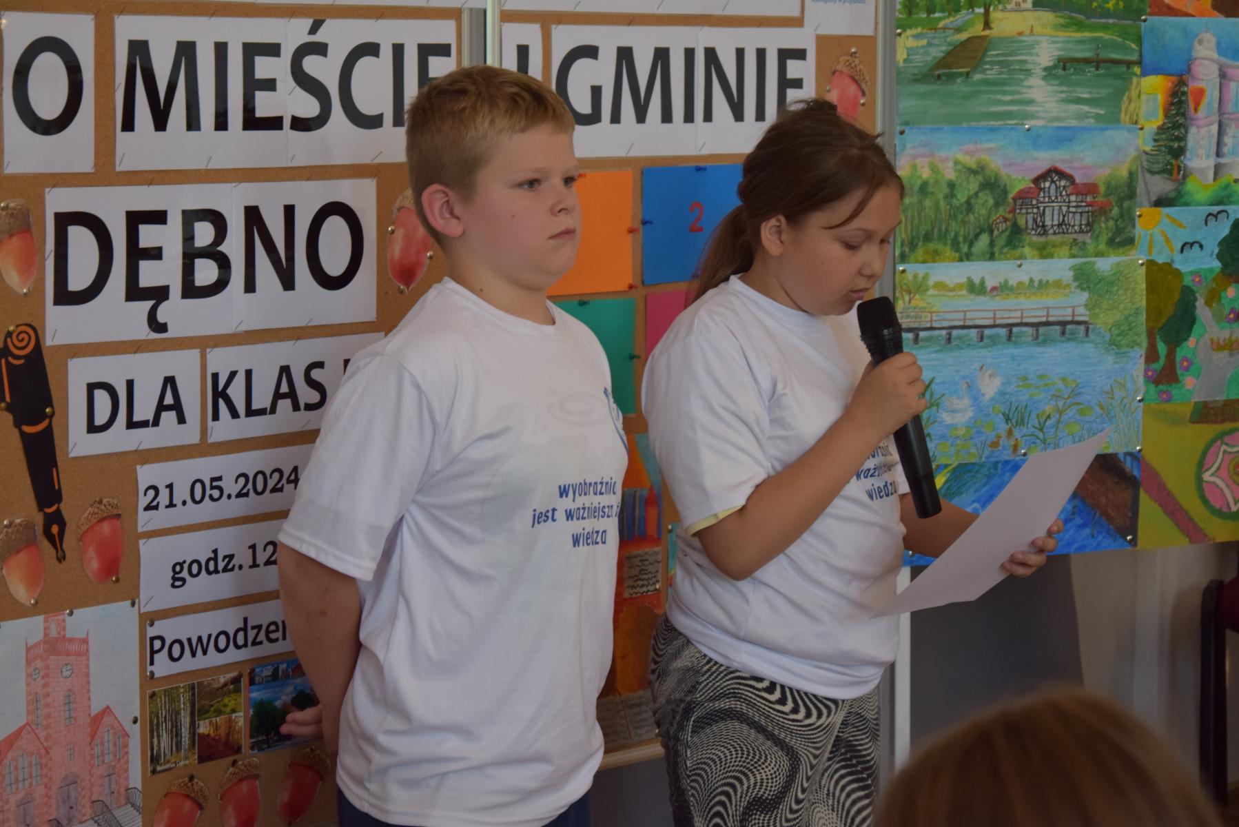 Uczeń i uczennica, która czyta wierszyk z kartki