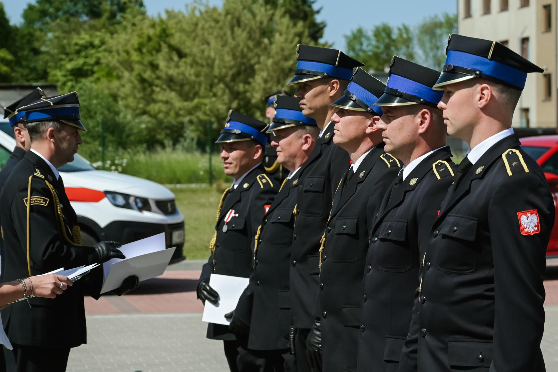 Strażacy stoją w szeregu , po drugiej stronie komendant 