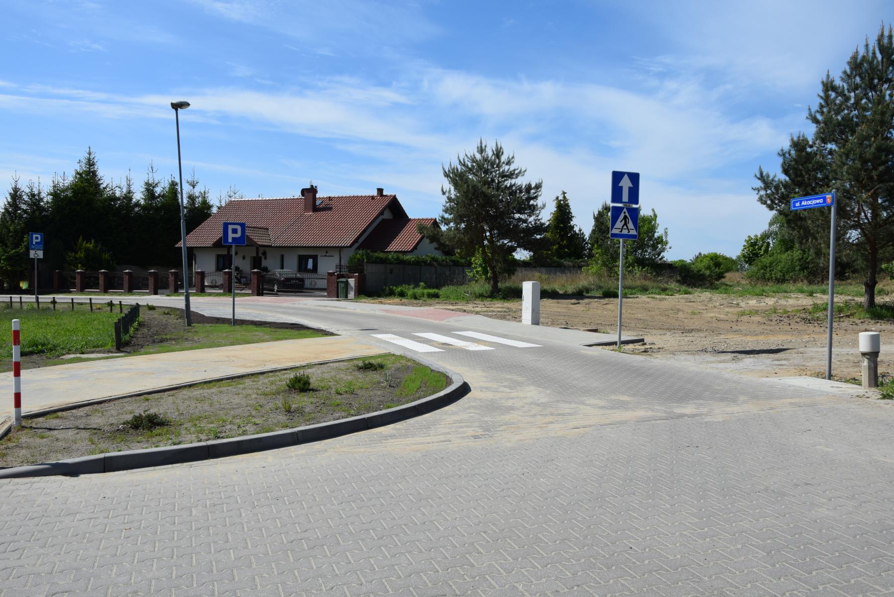 Ulica Akcajowa przy palcu zabaw. W oddali znaki parking