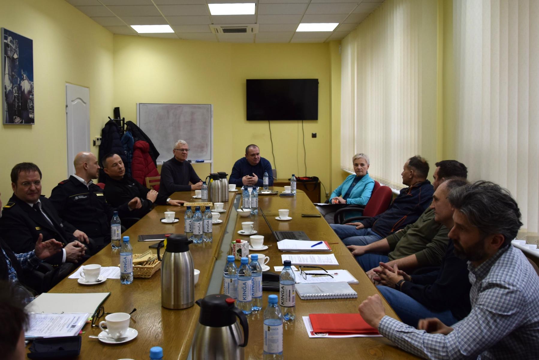 Osoby siedzą przy stole konferencyjnym 