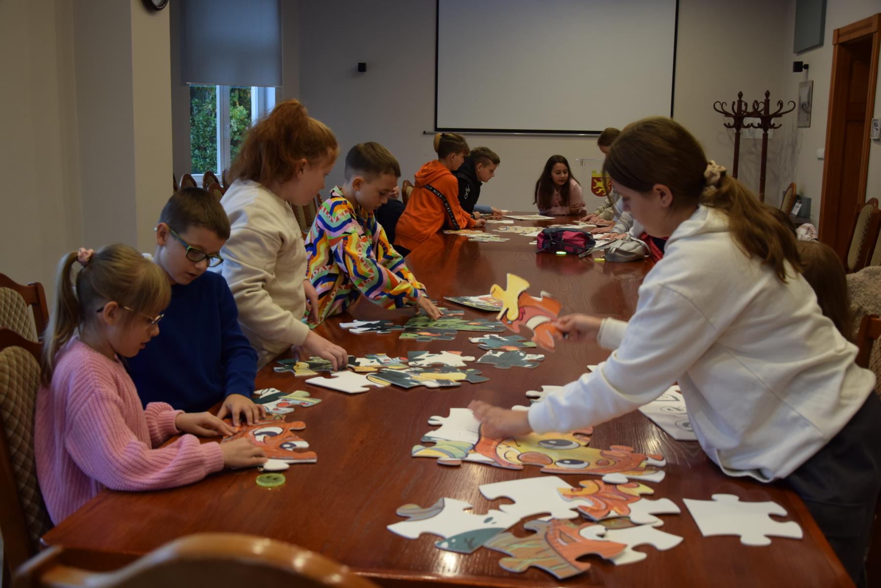 Dzieci na stole układają puzzle na stole w sali posiedzeń 