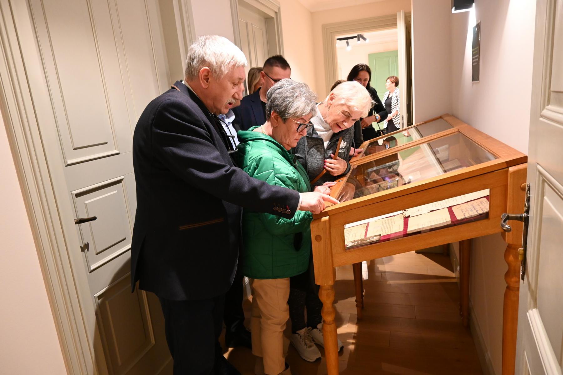 Zwiedzący oglądają dokumenty w gablocie. 