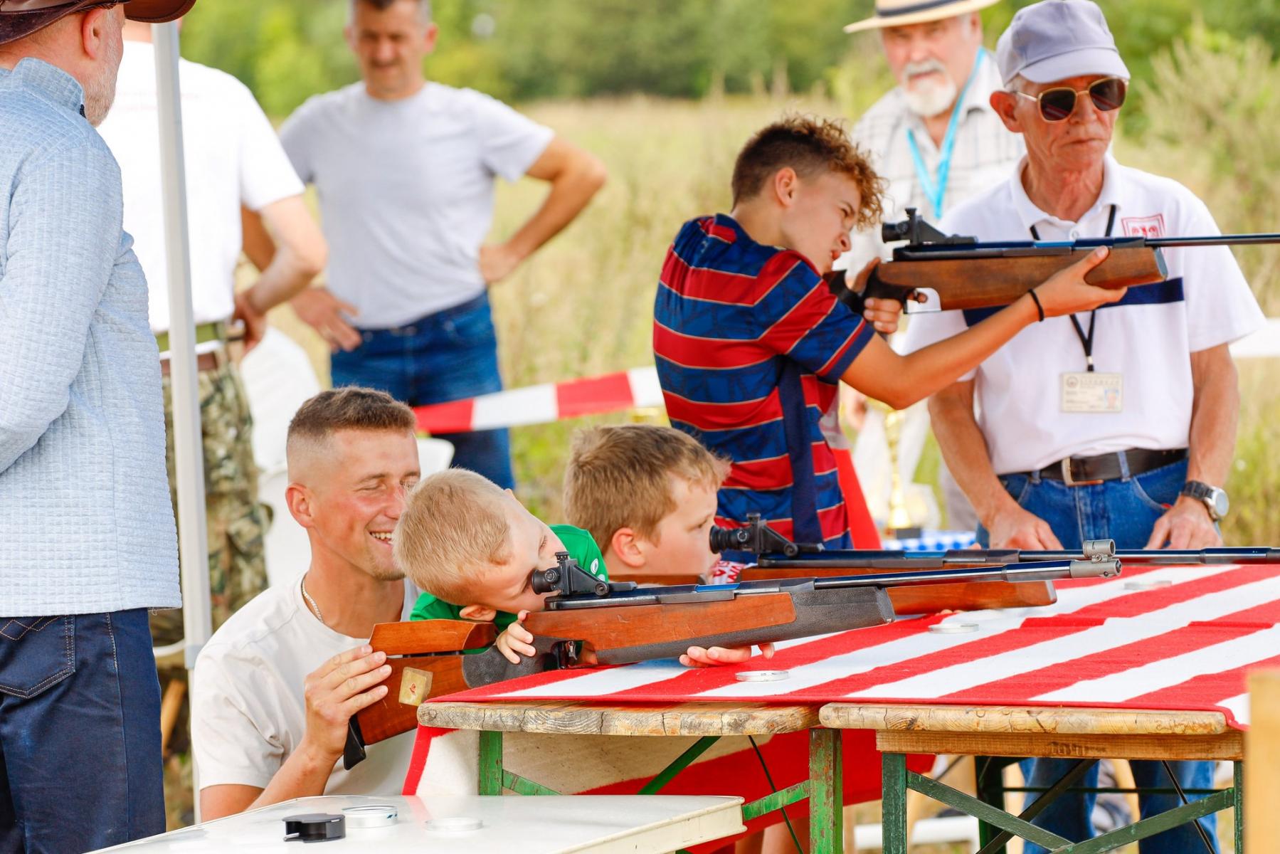 Dzieci strzelają na strzelnicy. Trzymają wiatrówki