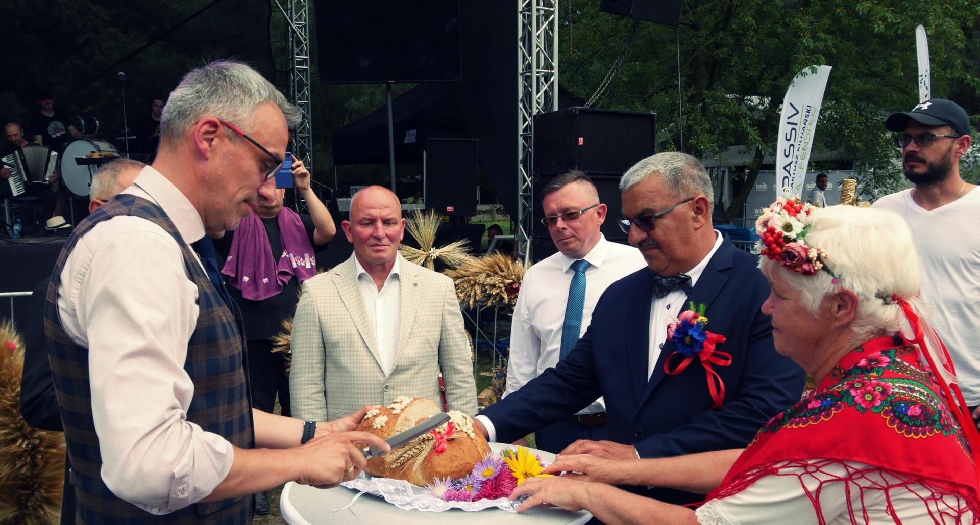 Burmistrz Dębna kroi chleb, na przeciwko stoją starstowie dożynek 