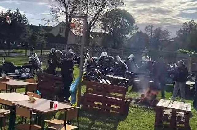 Motocykle ustawione na placu, ognisko, stoły