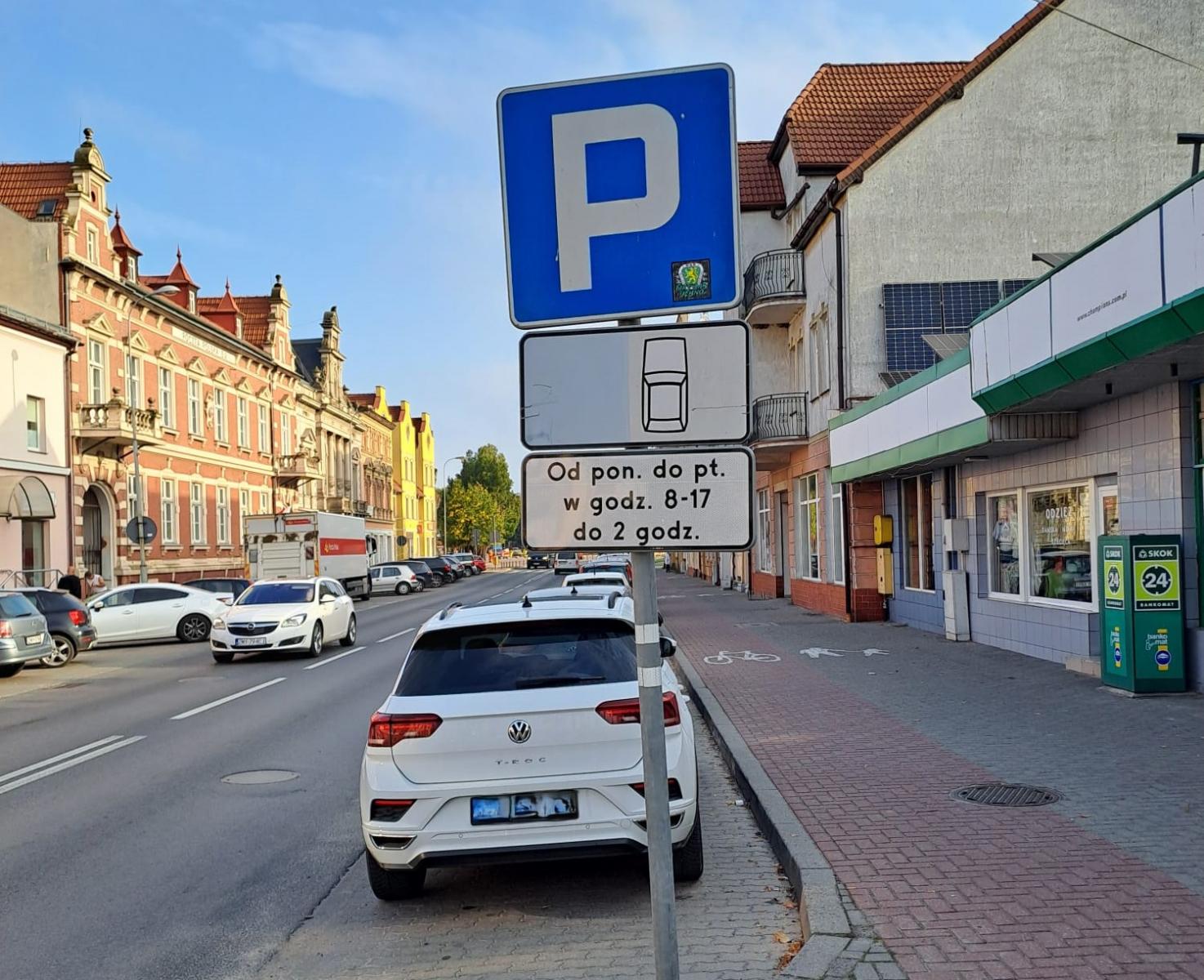 Miejsca postojowe, znak drogowy Parking, po obu stronach budynki