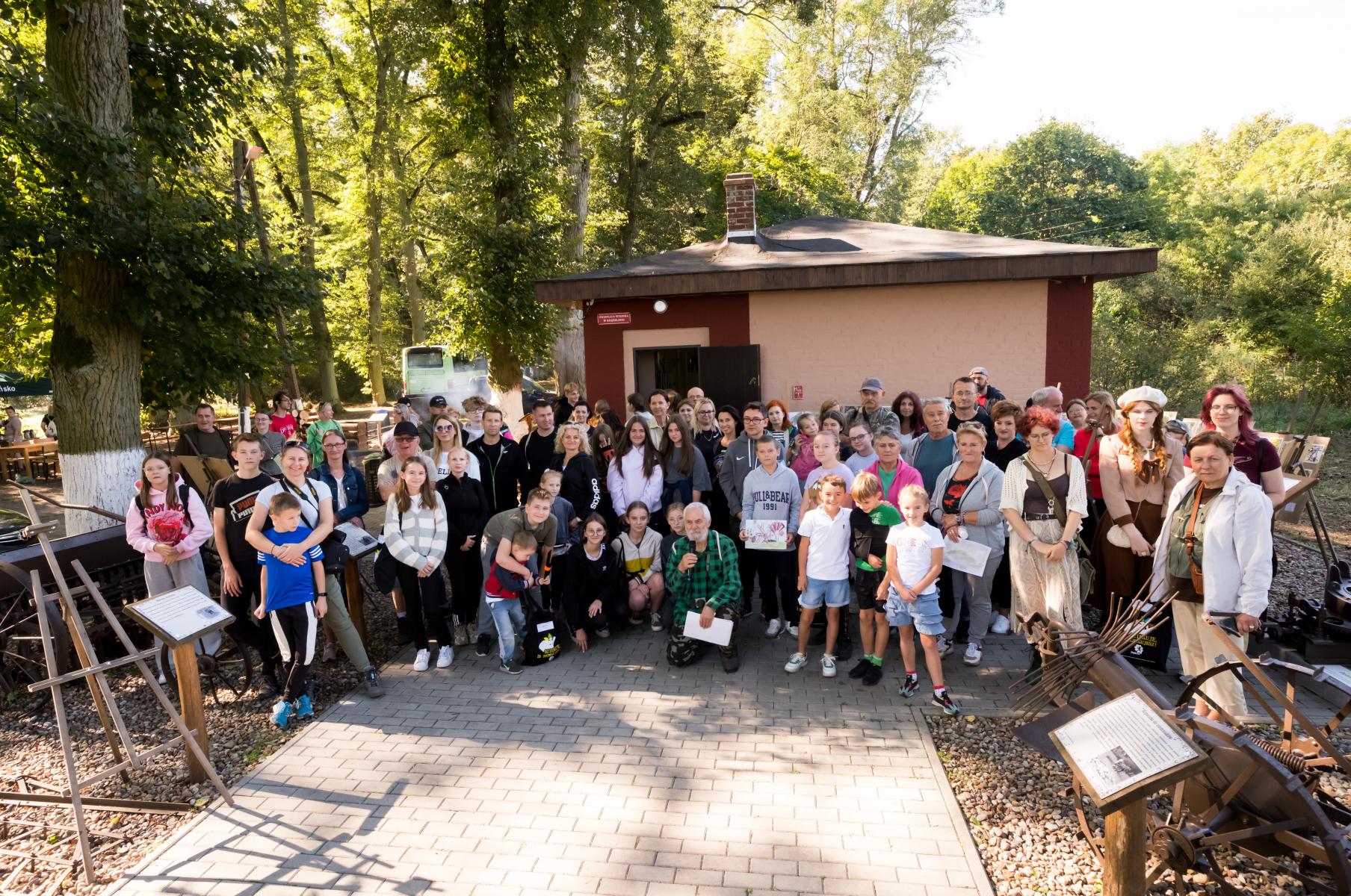 Grupowe zdjęcie kilkudziesięciu osób, w tle budynek świetlicy