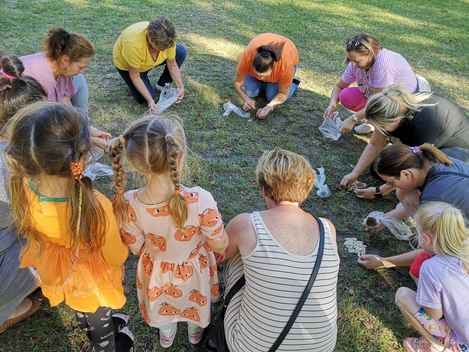 Kobiety kucają, wybieraja coś z woreczków.
