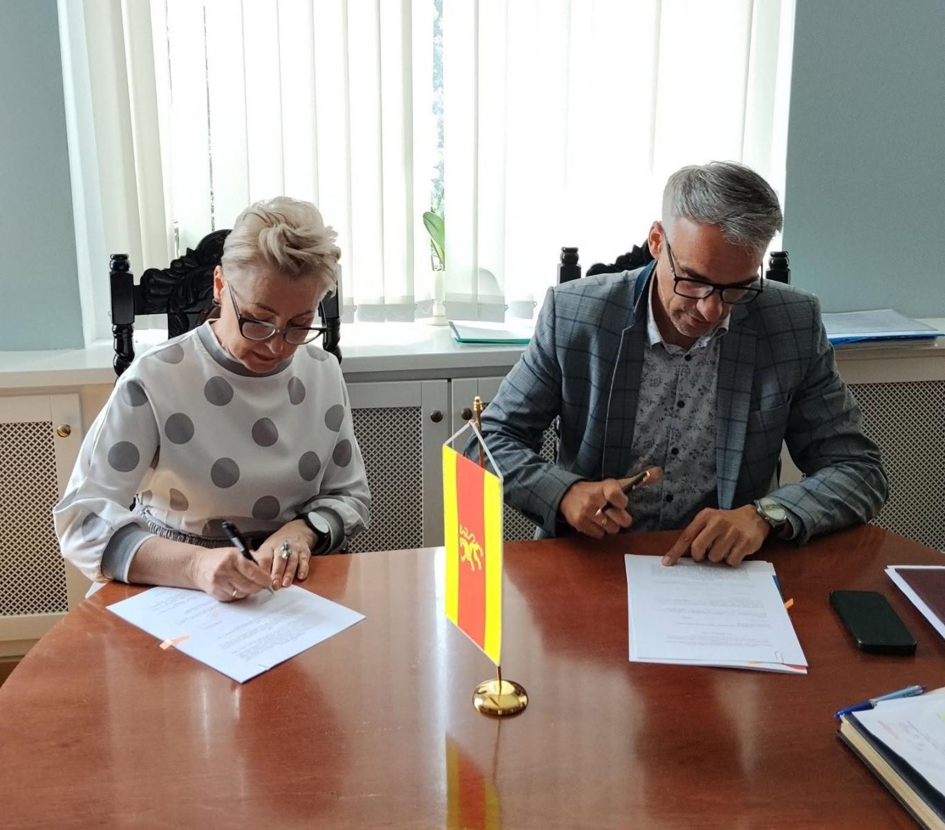 Prezes Zaepsołu mali Cychrowiacy i Burmistrz Dębna siedzą w gabinecie przy stole i podpisują umowę 