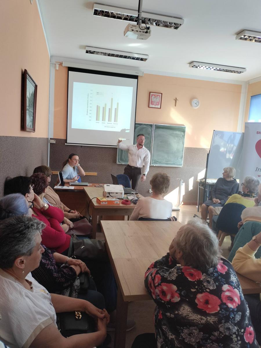 Prelegent stoi w sali, uczestnicy siedzą 