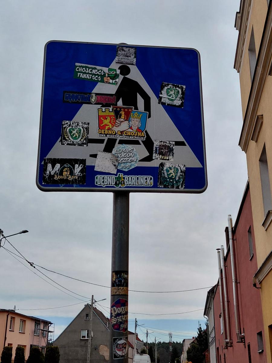 Znak przejście dla pieszych zaklejony naklejkami 