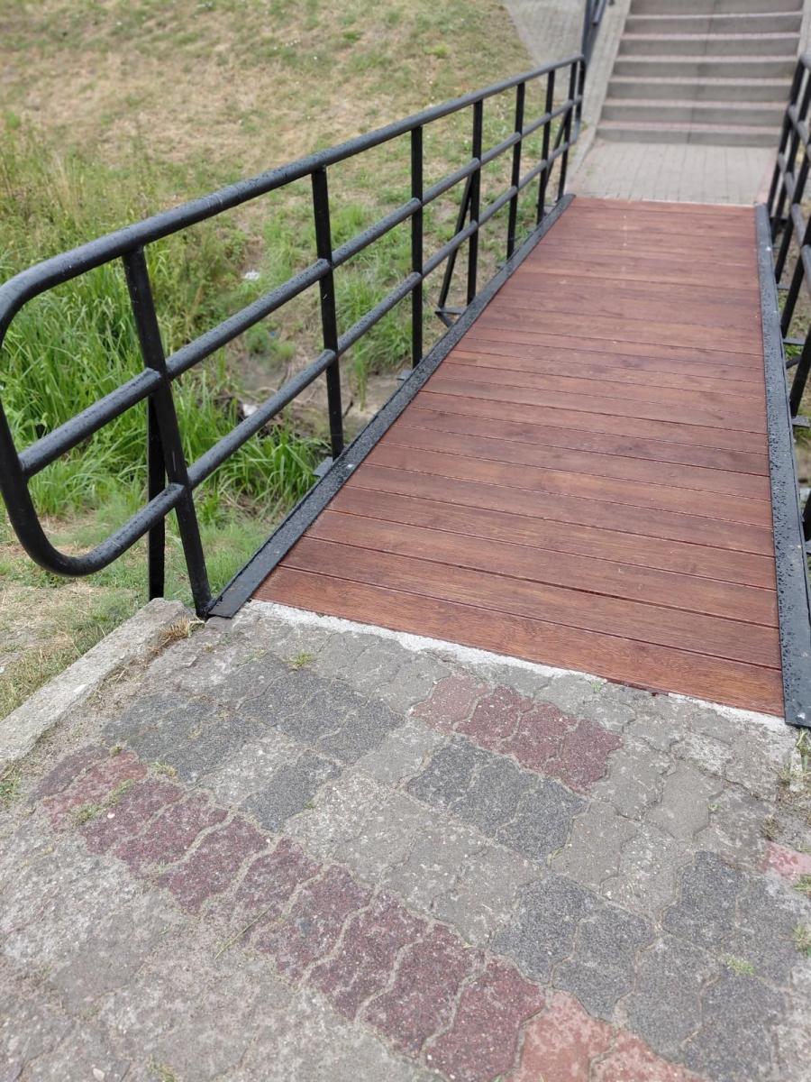 Kładka brązowa nad rzeczką, czarne barierki