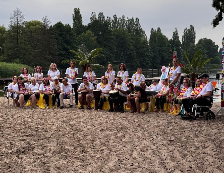Uczestnicy na plaży siedzą na krzesełkach grają na insturmentach 