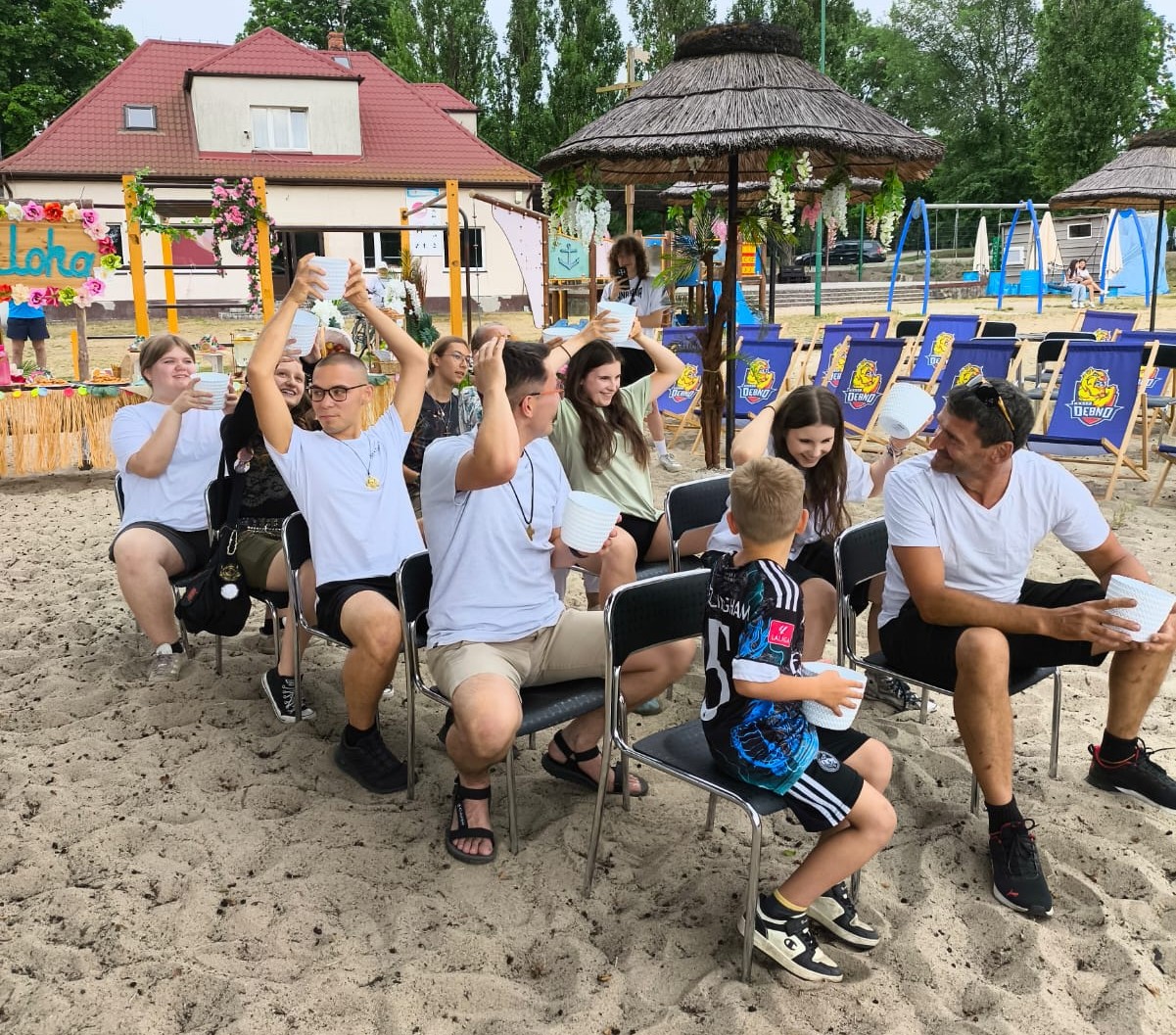 Wolontariusze z Oratorium siedzą na krzesełkach na plaży