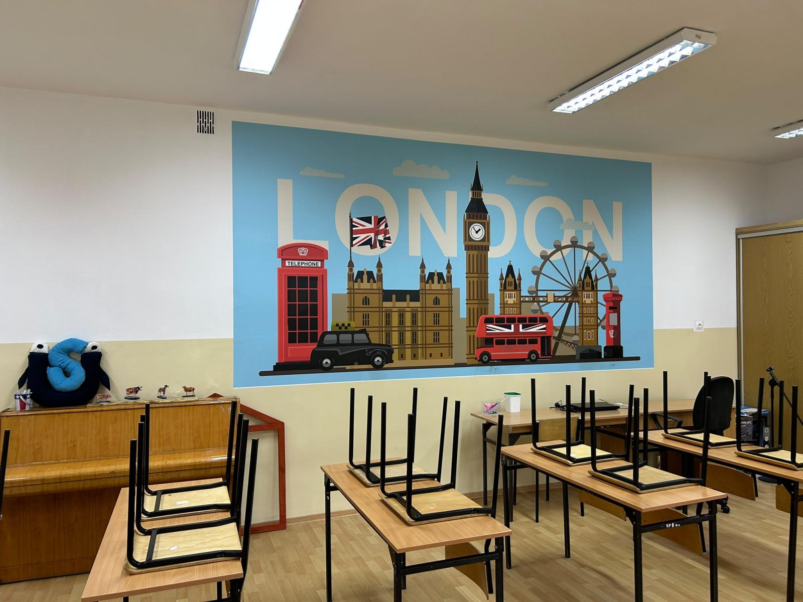 Odnoiwona sala lekcyjna z ławkami, na ścianie naklejka Londyn