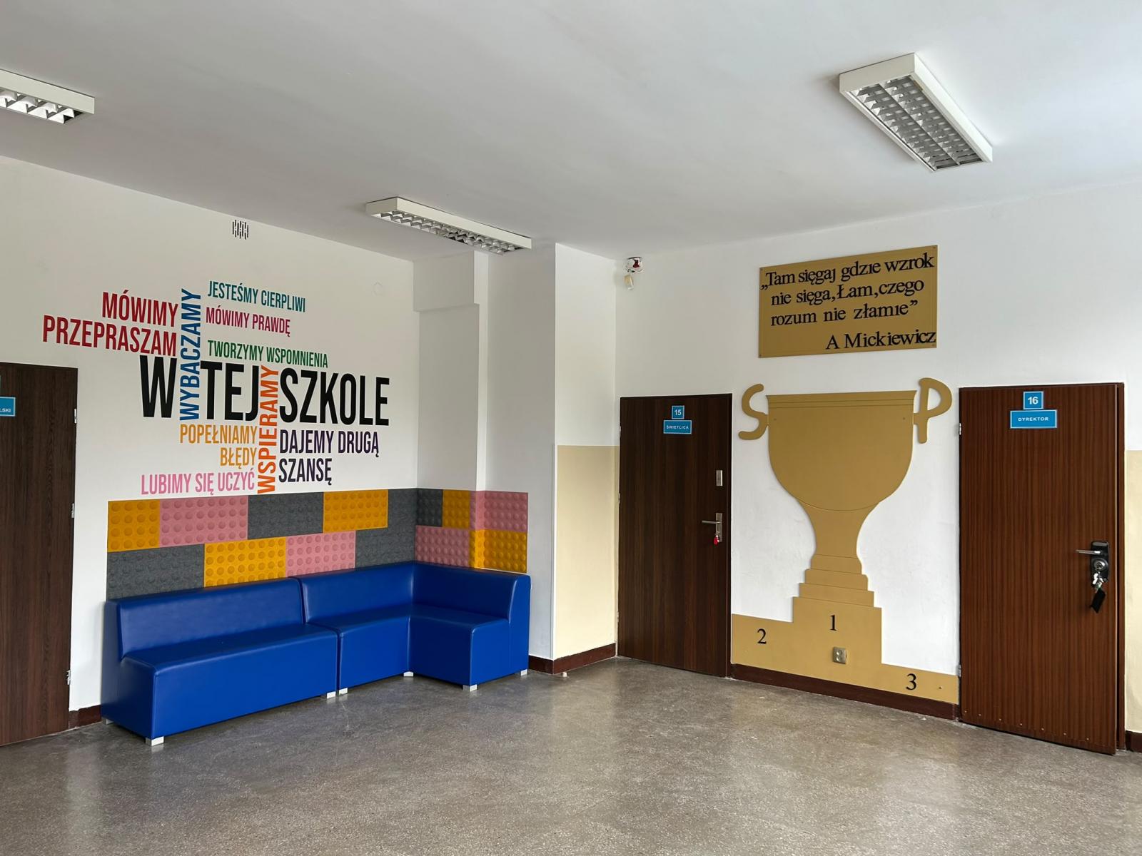 Hol skzolny z kolorywymi naklejkai na ścianach, w rogu stoi narożnik grantowy 
