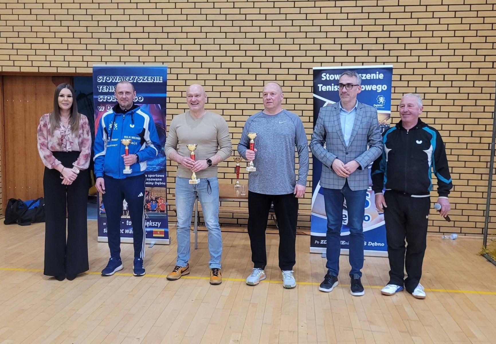 Od lwej na hali stojhą: pani dyrekotr OSiR, trzech mężczyzn z pucharami, burmistrz i prezes STS