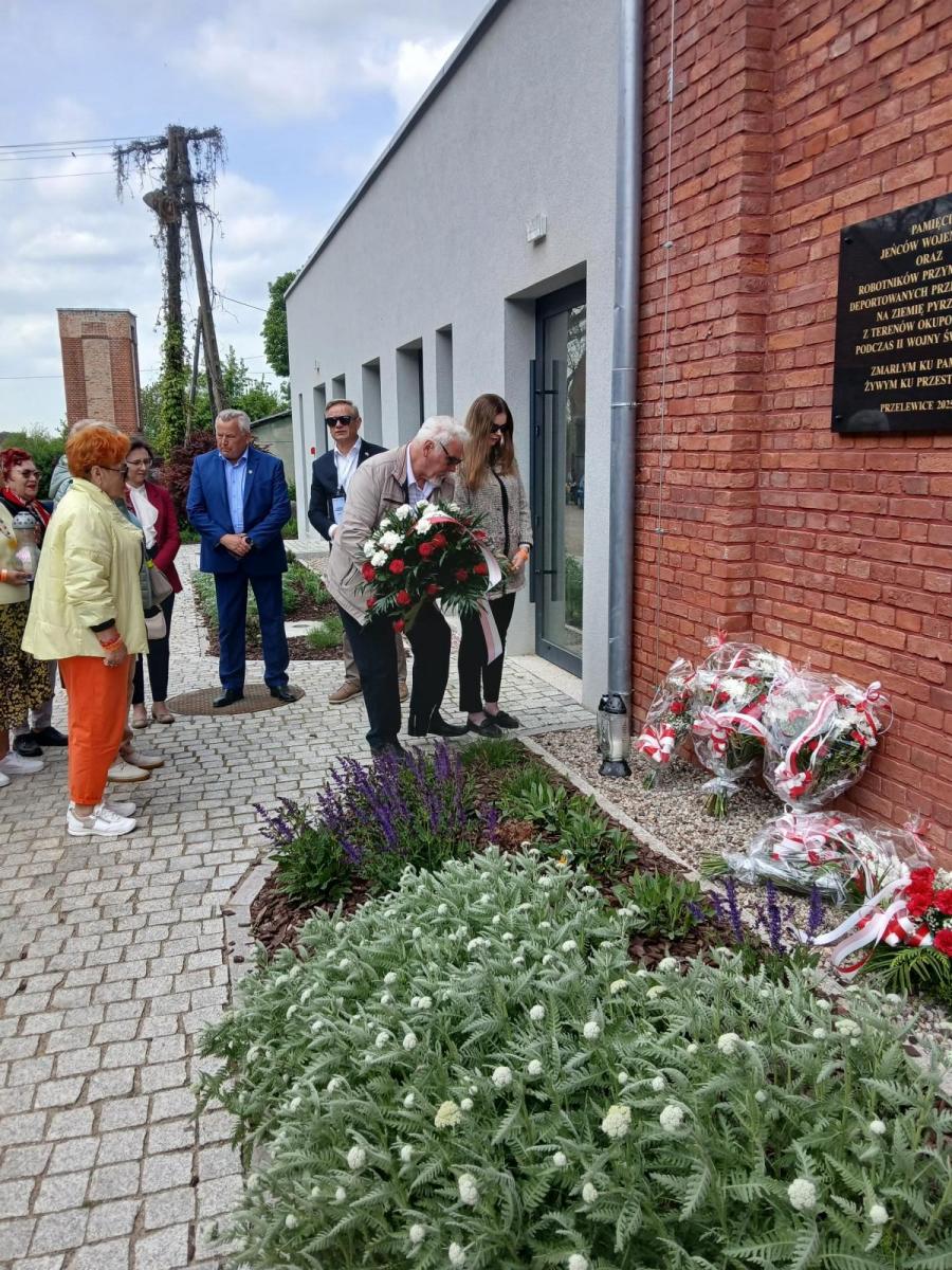 Mężczyzna składa kwiaty przy pamiątkowej tablicy