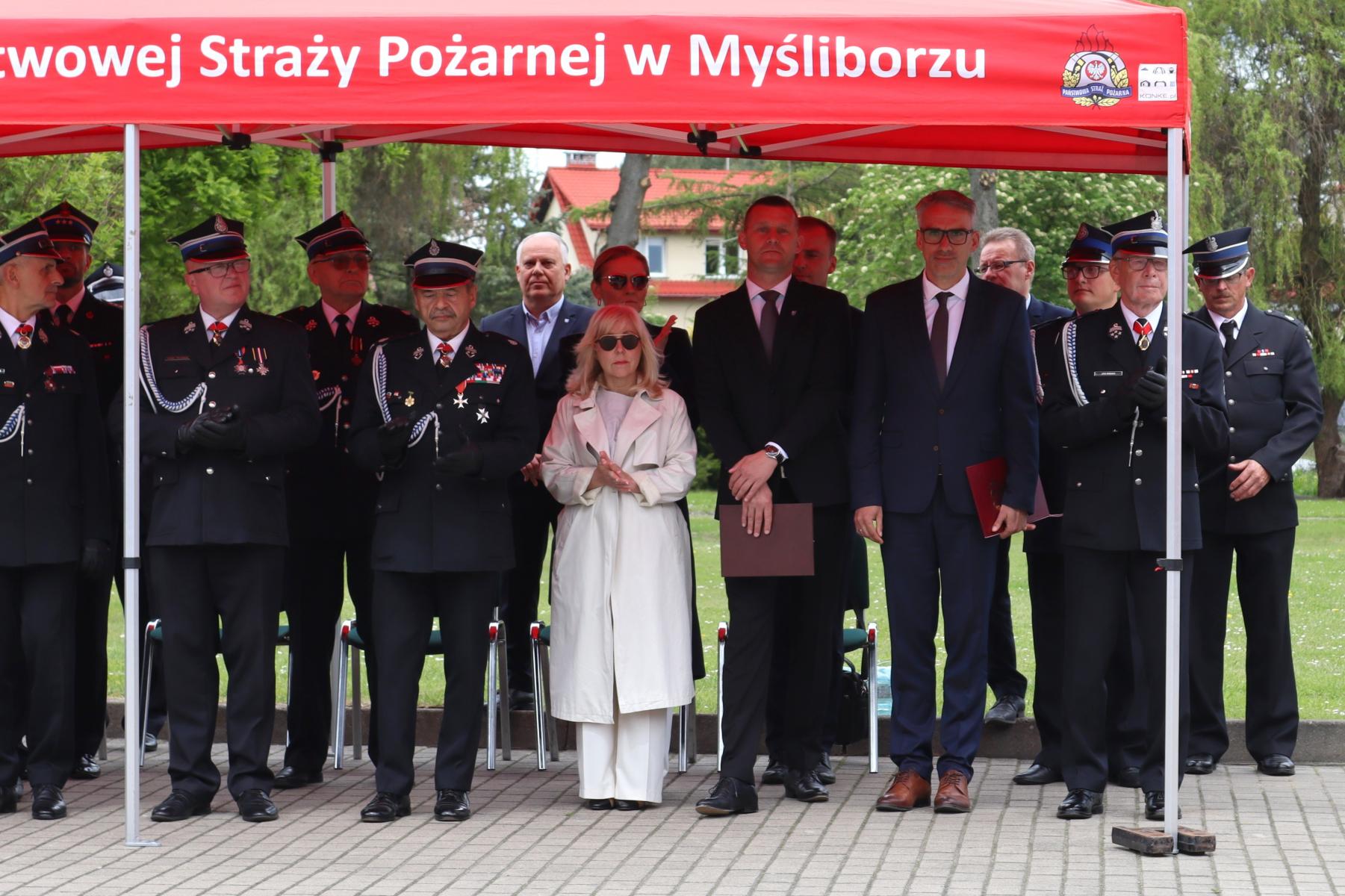 Goście stoją pod czerownym namiotem 