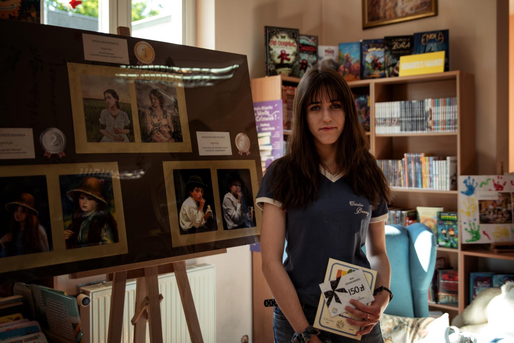 Hanna Jędrzejewska stoi w sali, w tle jej praca