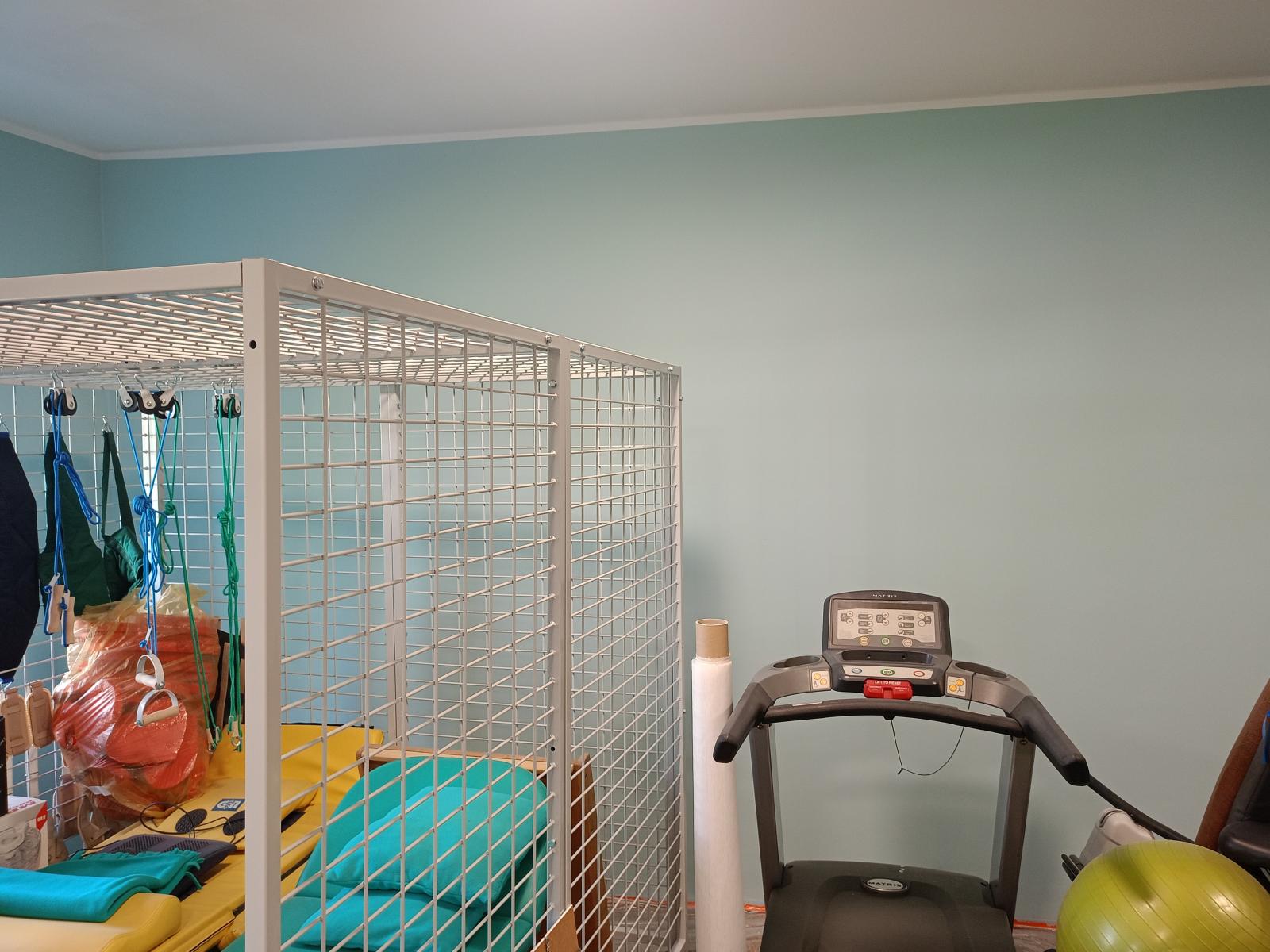 Sala rehabilitacji pomalowana na zielono, widoczne urządzenia
