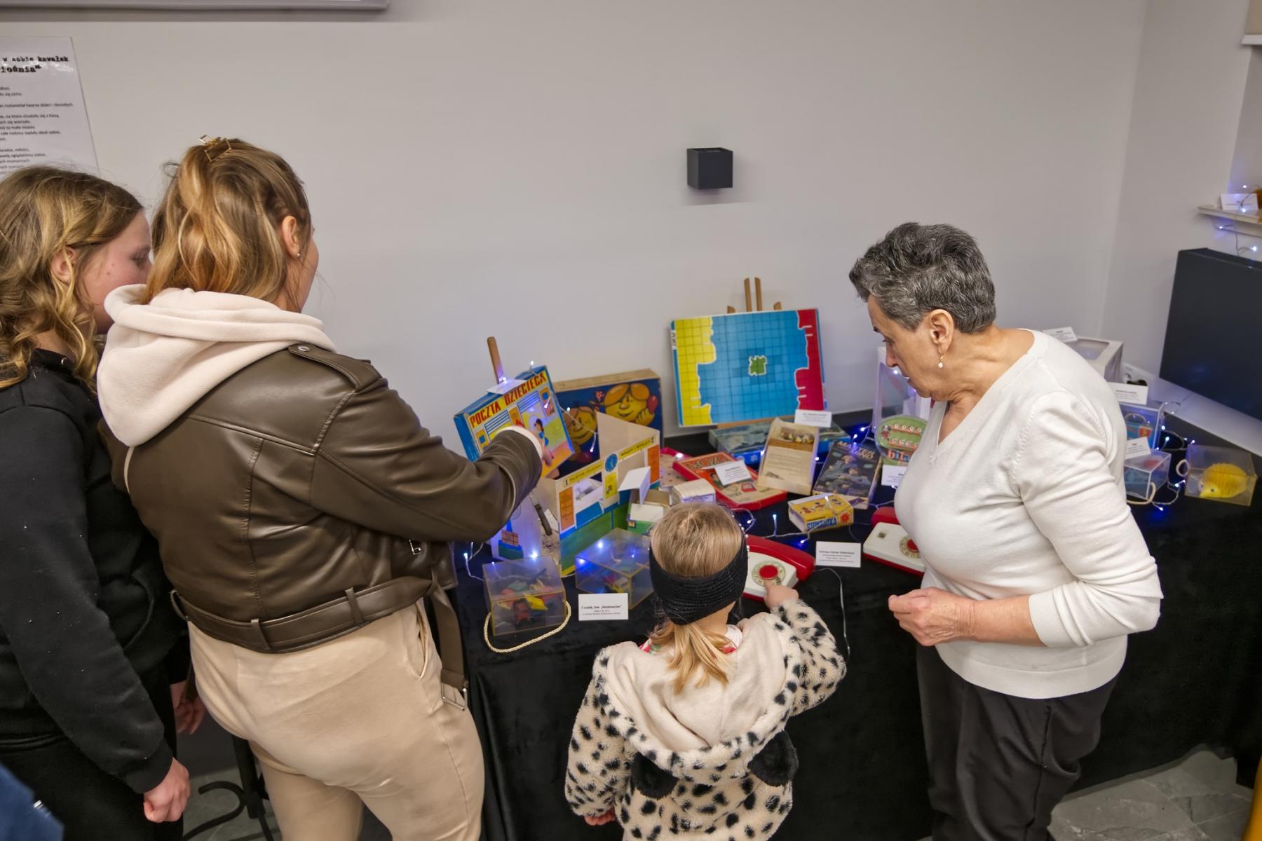 Ludzie stoją nad wystawą starych zabawek, gier planszowych