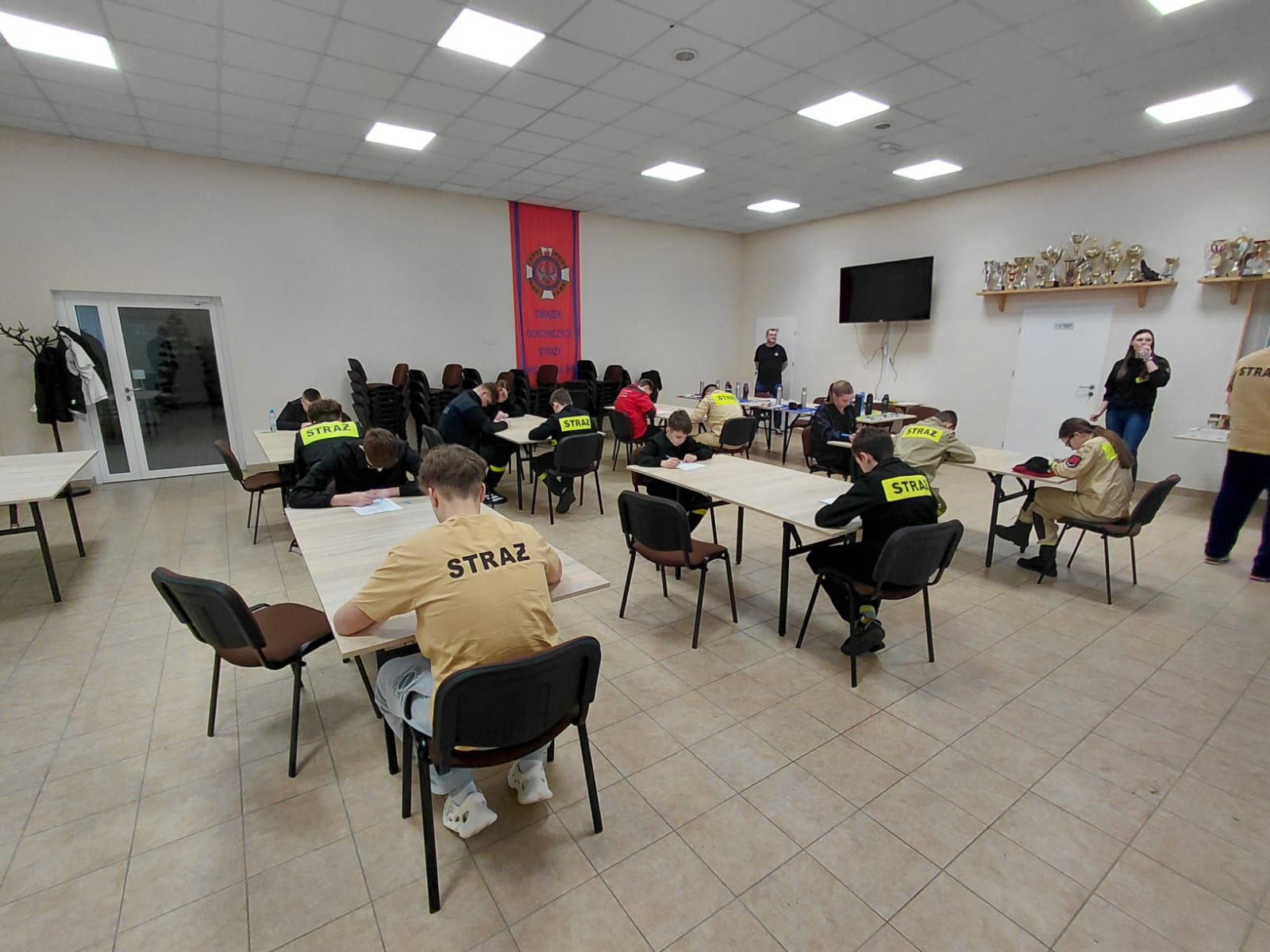 Uczestnicy druhowie siedzą przy stolikach w sali 