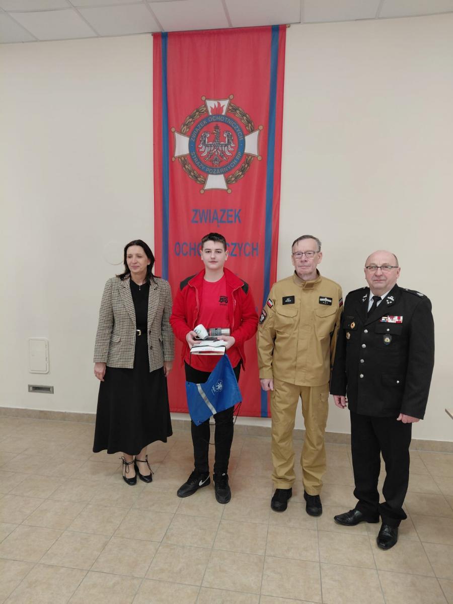W sali stoją: pani wiceburmistrz, chłopiec, prezes ZOSP, komendant OSP 