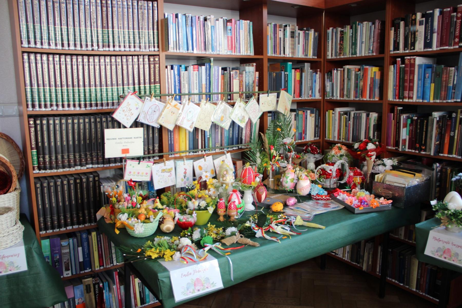 Rękodzieła, kartki, leżą na stole, w tle regały z książkami