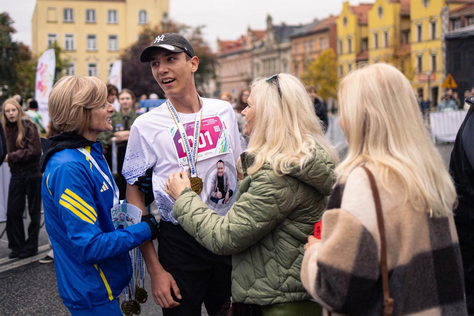Biegacz stoi z Wandą Panfi i innymi kobietami, w tle budynki