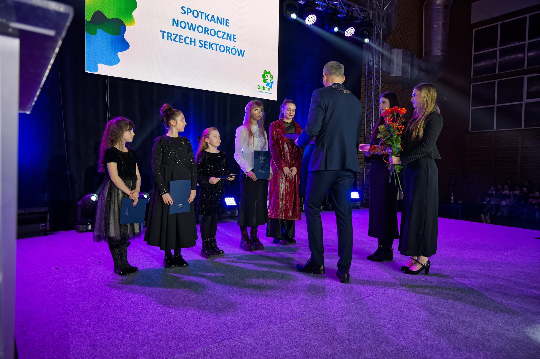 Dziewczyny na scenie burmistrz wręcza kwiaty i dyplomy
