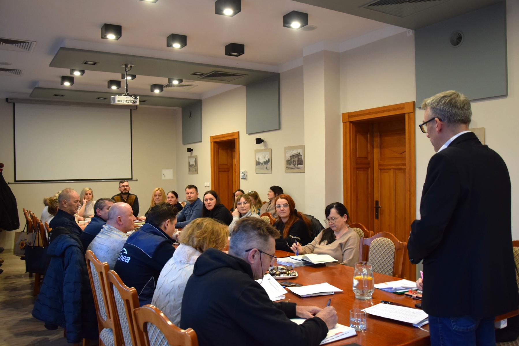 Ludzie siedzą w sali przy stole. 