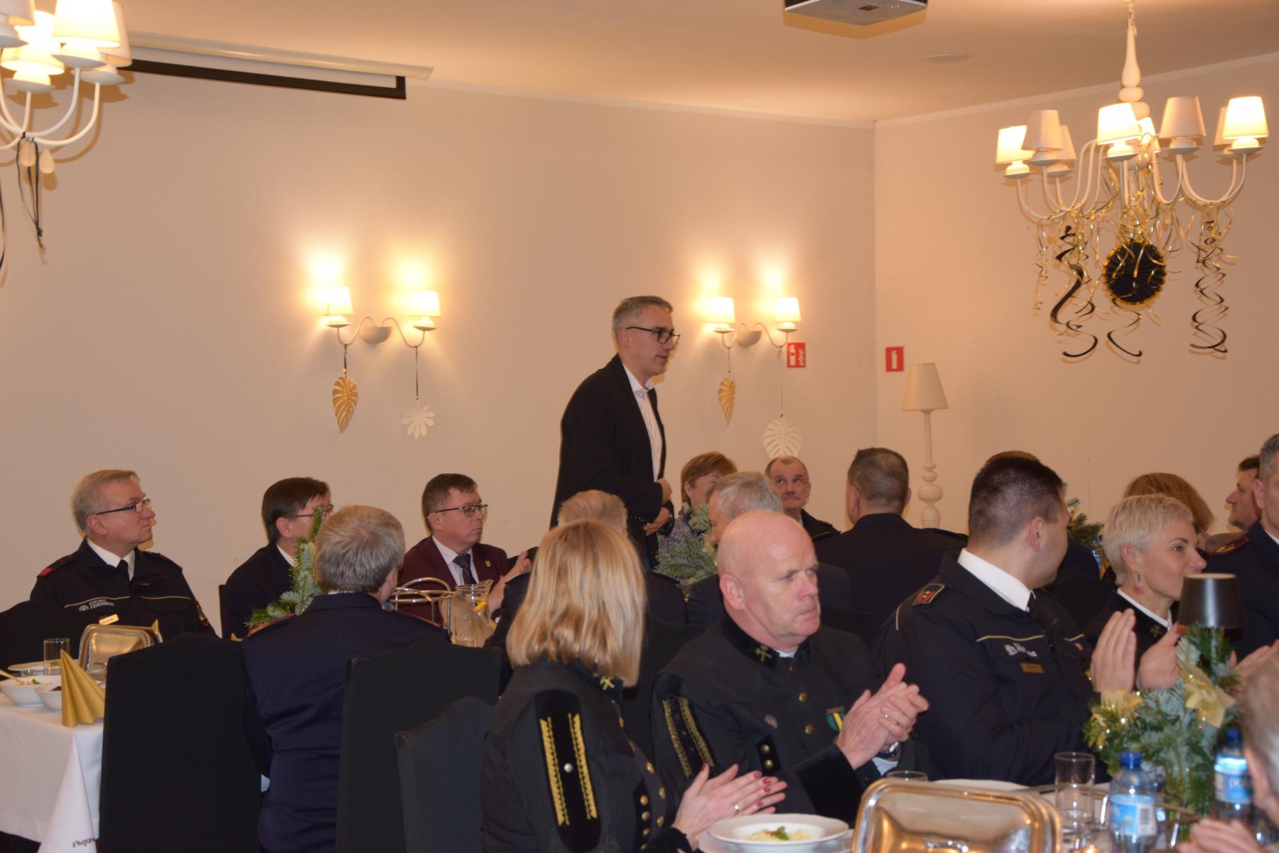 Goście siedzą w sali przy stołach, stoi burmistrz Dębna