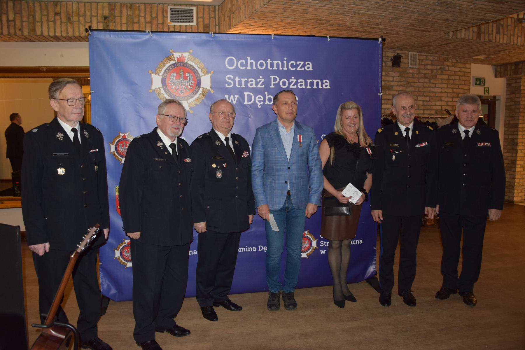 Wyr&oacute;żnione osoby stoją na tle baneru OSP Dębno