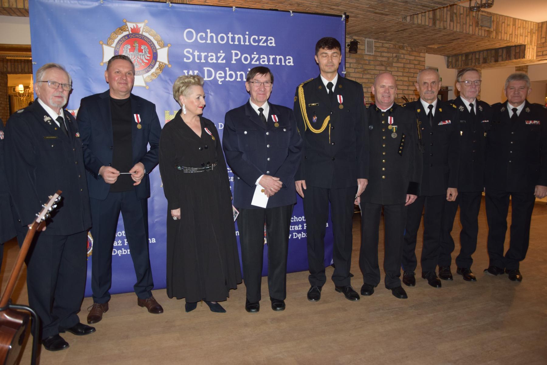 Wyr&oacute;znione osoby w mundurach stoja na tle baneru OSP Dębno 