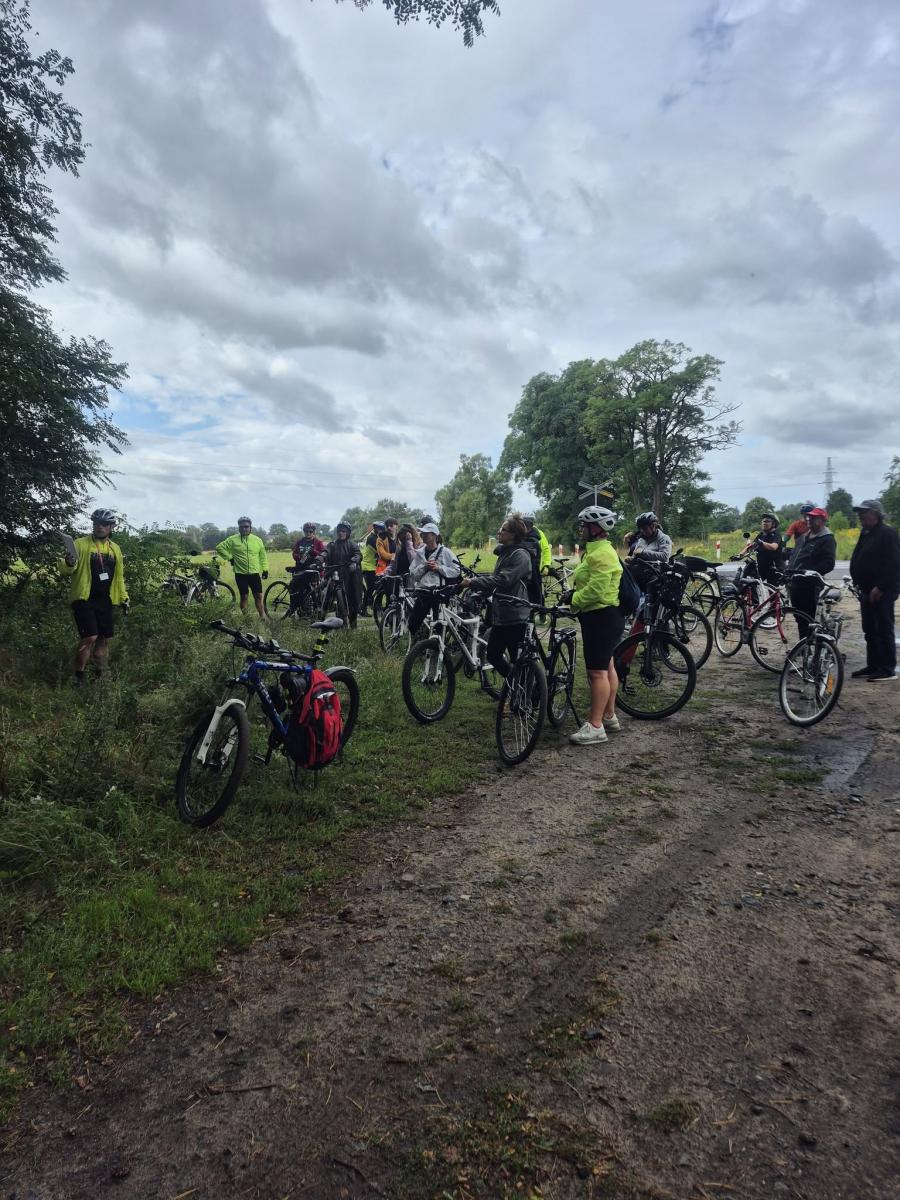 Uczestnicy rajdu rowerowego stoją na polnej drodze