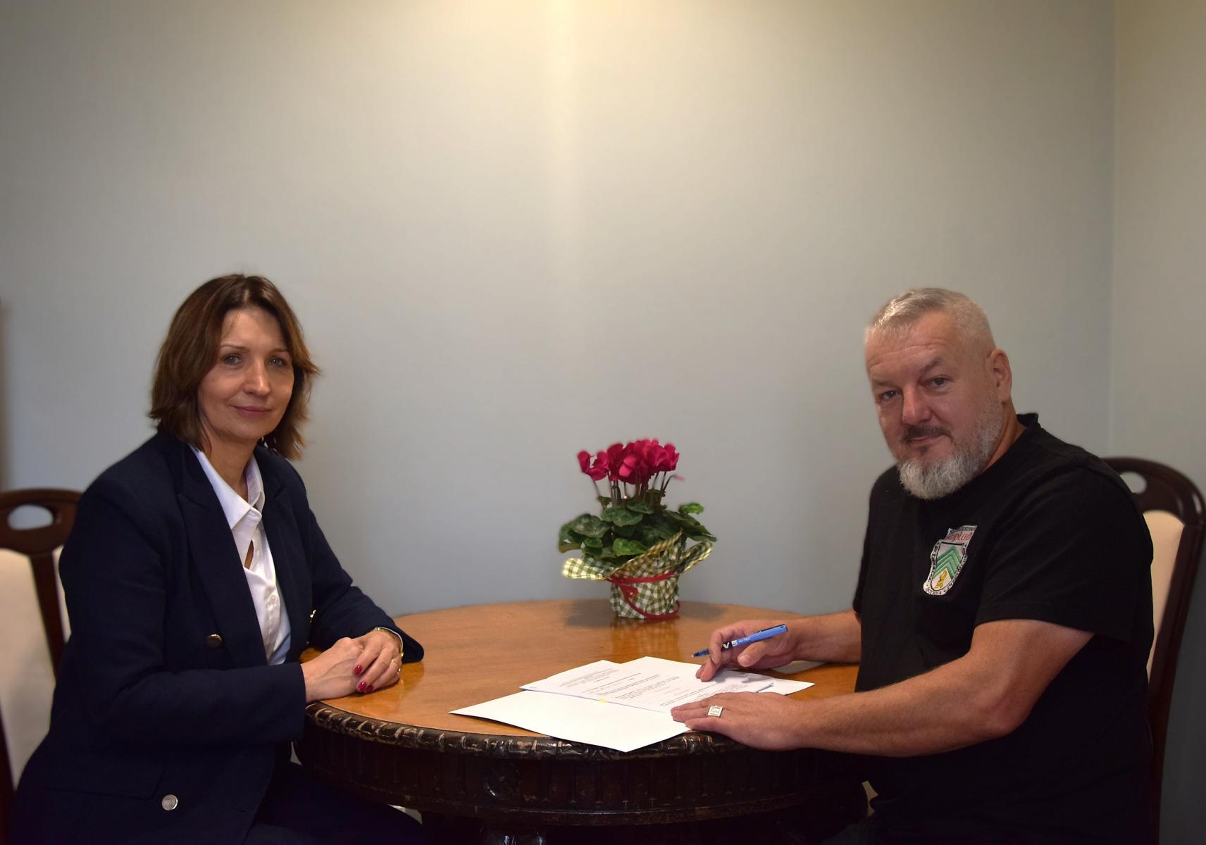 W gabinecie przy stoliku siedzą pani wiceburmistrz i przedstawiciel stowarzyszenia. Na stoliku leżą dokumenty