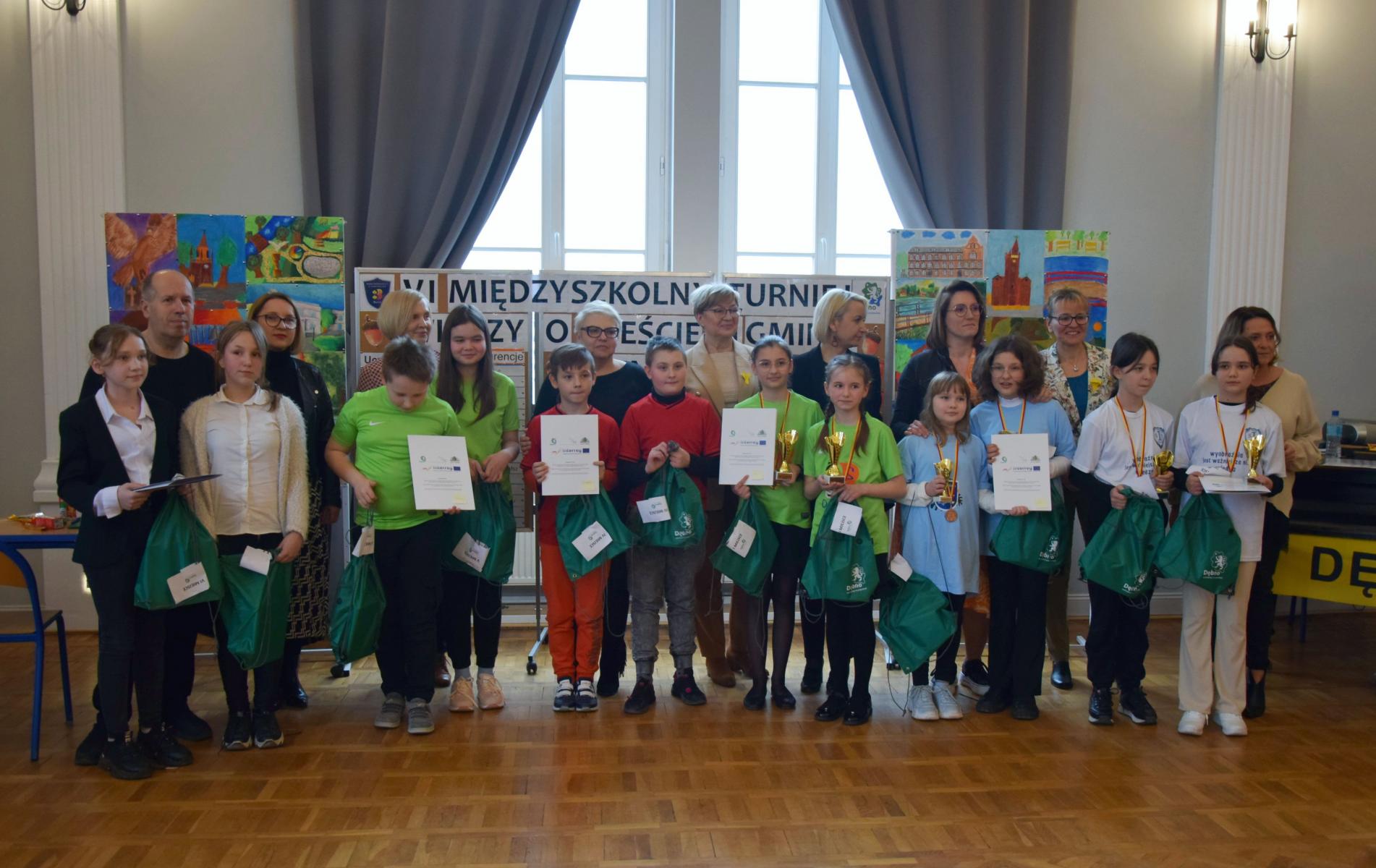 Grupowe zdjęcie drużyn z nagrodami i opiekunami i jury